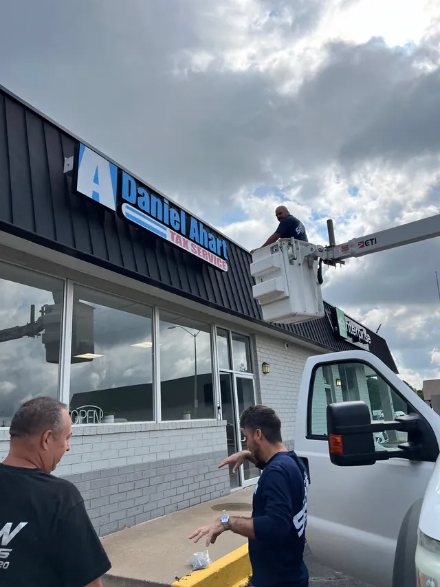 The W&W crew installing a storefront sign from a bucket truck